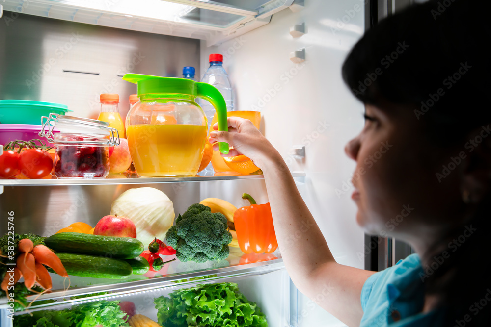 Open refrigerator door. The woman takes a jug of juice from the shelf. Freshly squeezed orange juice in a jug. Open refrigerator door. The woman takes a jug of juice from the shelf. Freshly squeezed orange juice in a jug.