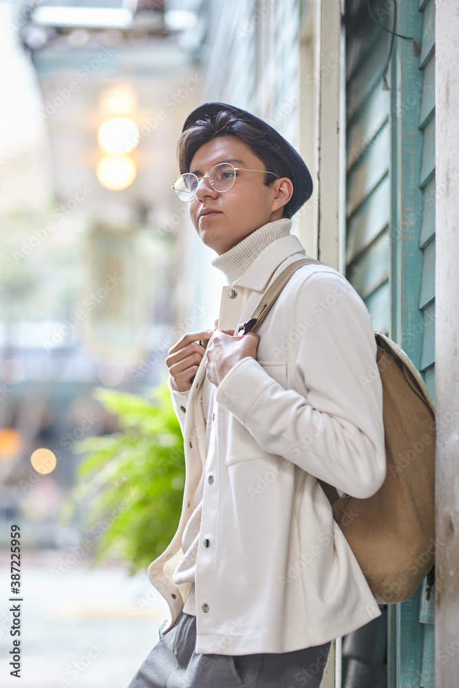 Fototapeta premium Stylish man wearing white sweater and jacket and standing on street