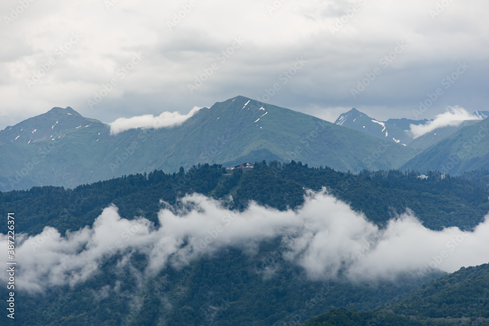 Beautiful landscape of mountain peaks shrouded in clouds. Nature of Europe in cold colors.