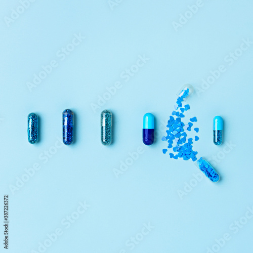 Layout made of blue pills and capsules on pastel table. Covid-19 or Coronavirus minimal art concept. Creative medication and prescription pills flat lay background.