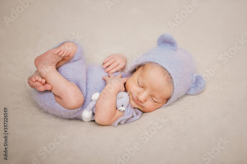 newborn boy dressed as a gray mouse sleeping with a toy
