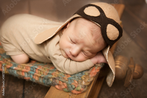 newborn boy in a pilot costume sleeps on a vintage airplane