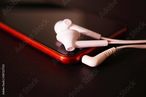 Obraz na płótnie Earphones on red smartphone close up. w salonie