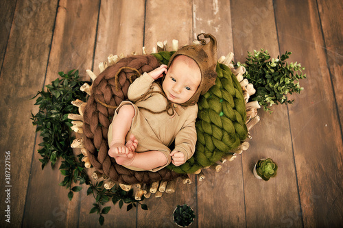 a newborn boy 12 days old in an elf kitten lies in a basket
