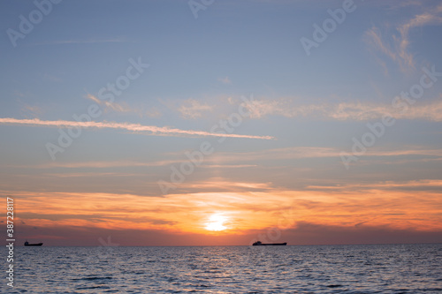 silhouettes of ships at sea at sunset