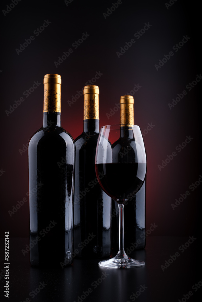 wine bottles and full glass with red and black background