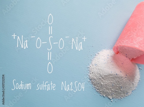 Structural chemical formula of sodium sulfate molecule with laundry washing powder detergent with blue sodium sulfate speckles. Sodium sulfate is mainly used for the manufacture of detergents.