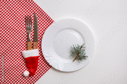 Traditional Christmas table place setting with empty white plate  linen napkin  cutlery with festive decorations. New Years background and Holiday concept. Flat lay  top view with copy space