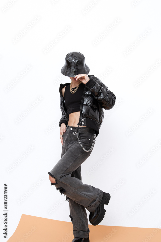 Sexy model in fashion urban street outfit. Trendy black bucket hat and bomber. Ripped jeans. Platform boots. Stylish Fall winter seasons. Back in 90s Girl Sexy model in fashion urban street outfit. Trendy black bucket hat and bomber. Ripped jeans. Platform boots. Stylish Fall winter seasons. Back in 90s Girl