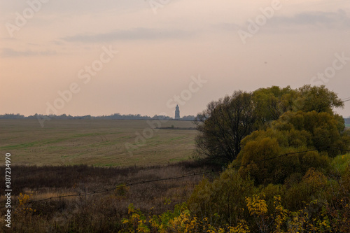 Top view on country landscape with tower, field, trees in sunny autumn evening