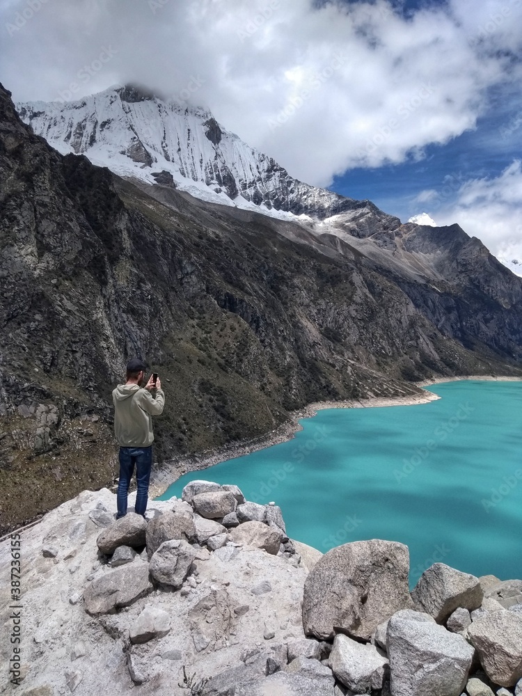 Man at Laguna Paron, Huaraz, Peru. A blue-green lake in the Cordillera Blanca on the Peruvian Andes. At 4185 meters above sea level, it's surrounded by snowy peaks and a pyramid mountain. Man at Laguna Paron, Huaraz, Peru. A blue-green lake in the Cordillera Blanca on the Peruvian Andes. At 4185 meters above sea level, it's surrounded by snowy peaks and a pyramid mountain.