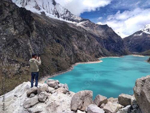 Man at Laguna Paron  Huaraz  Peru. A blue-green lake in the Cordillera Blanca on the Peruvian Andes. At 4185 meters above sea level  it s surrounded by snowy peaks and a pyramid mountain. 