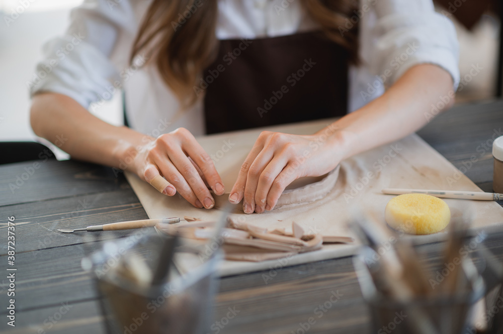 Artisan female potter prepares material for her pottery. Woman hands attach clay part to future ceramic product. Work close-up. Artisan female potter prepares material for her pottery. Woman hands attach clay part to future ceramic product. Work close-up.
