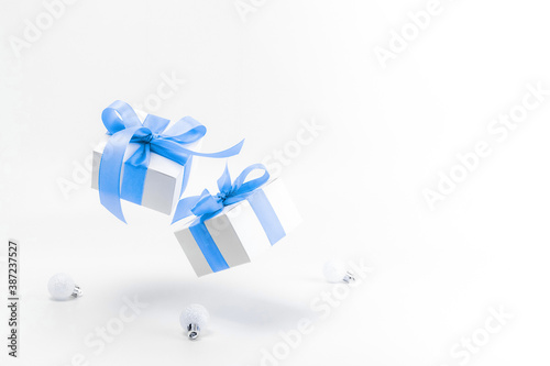 Winter sale. White gifts with blue ribbon and New Year balls in xmas decoration on white background for greeting card. Christmas, winter, new year concept.