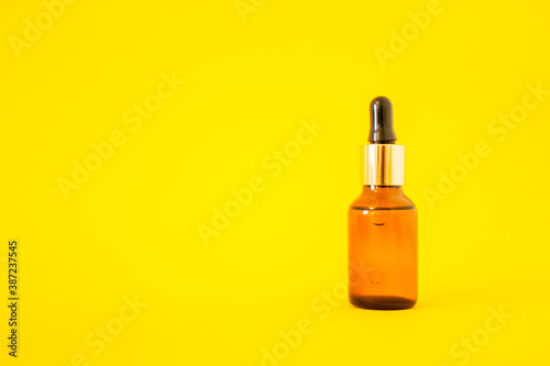 Cosmetic bottles with serum on a yellow background. Cosmetology and beauty concept.