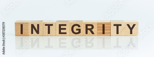 Wooden Blocks with the text: Integrity. The text is written in black letters and is reflected in the mirror surface of the table.