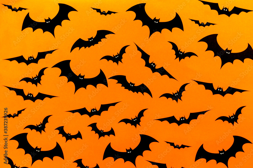 Many black bats on orange background.