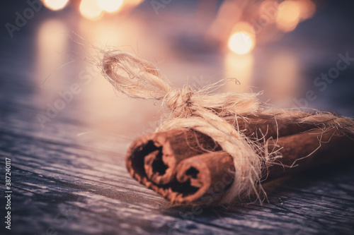 Close-up of a cinnamon stick around which a string is wrapped. autumnal tones and bokeh light in the background. holidays concept