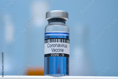 Coronavirus vaccine in bottle for injection on table against background medical laboratory, space for text. Defeating SARS-CoV-2 coronavirus epidemic. Scientists have found vaccine against coronavirus