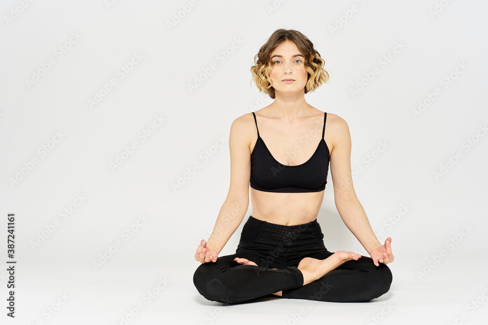 Woman in leggings meditate in a light room with her legs crossed yoga asana Woman in leggings meditate in a light room with her legs crossed yoga asana