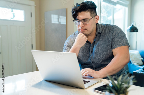 Man working from home on laptop computer sitting at kitchen counter