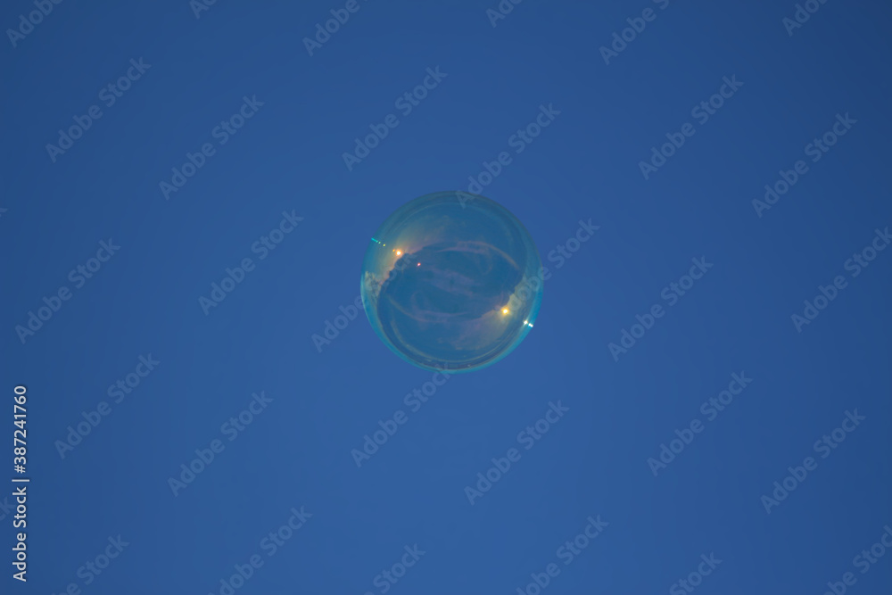 flying soap bubble with reflective rays of the sun on a blue sky background flying soap bubble with reflective rays of the sun on a blue sky background