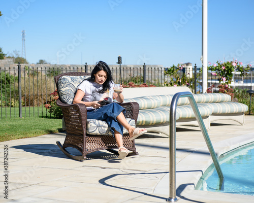 Woman sitting by a pool in yard working from home.