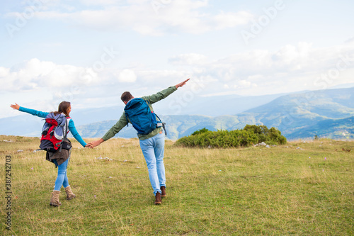 Happy travelers couple conquered top of mountain, raises hands up