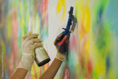 Making a painting: hands spraying color over objects