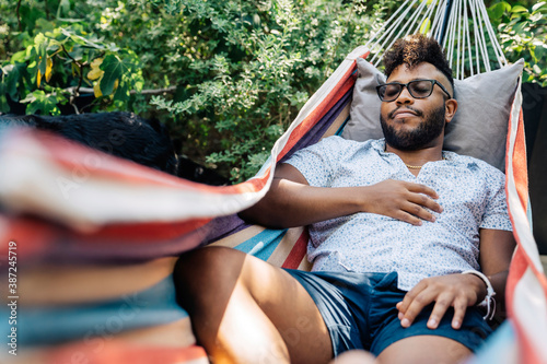 Black man napping in hammock in back yard