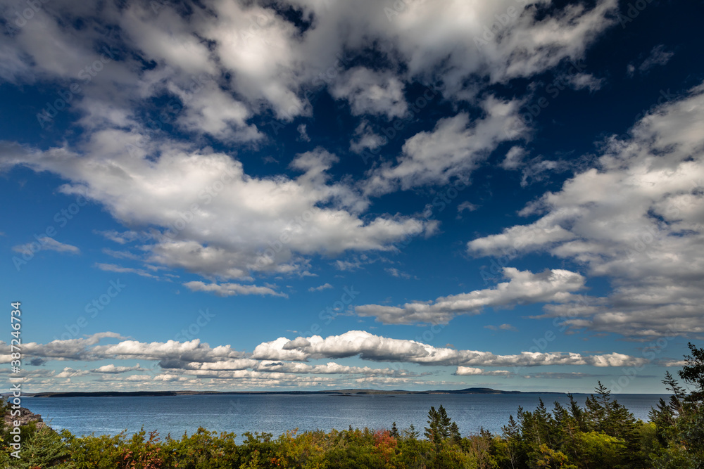 Obraz premium Soaring clouds over the ocean of Frenchman's Bay and the area surrounding Schooner Head Overlook in Acadia National Park, Maine