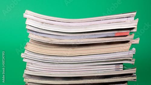  Large pile of books stacked together on green background.