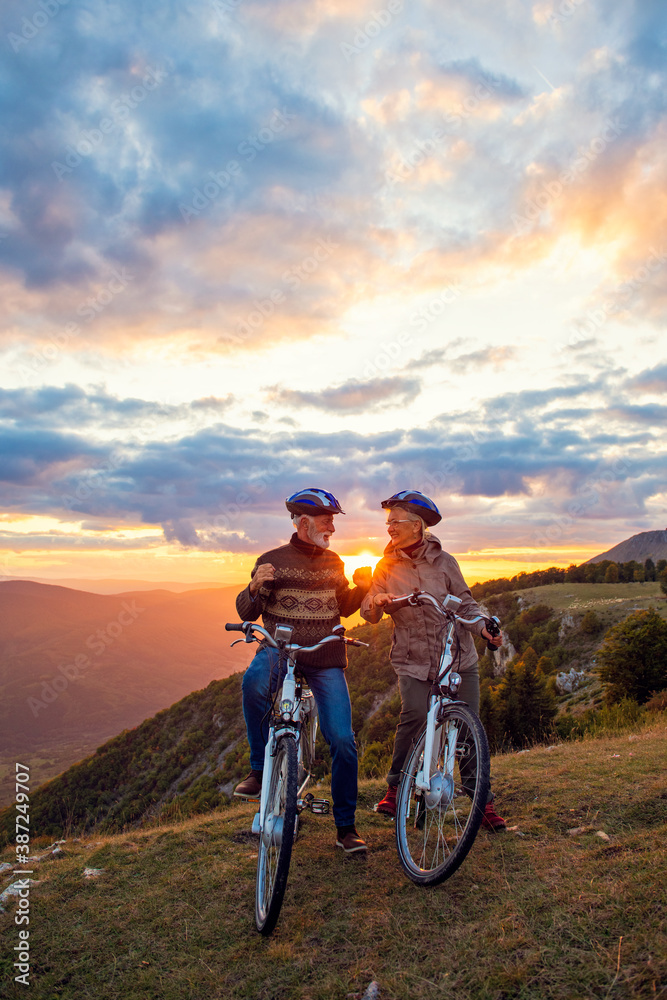 Active Senior Couple Riding Bikes In Park Active Senior Couple Riding Bikes In Park