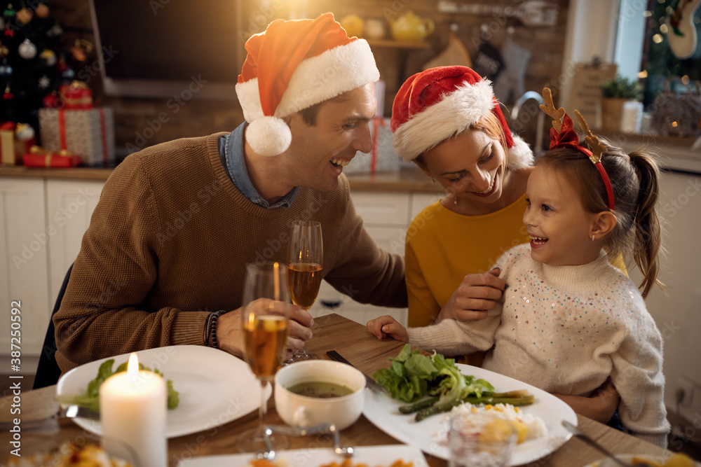 Happy parents and their small daughter having fun at dining table on Christmas. Happy parents and their small daughter having fun at dining table on Christmas.