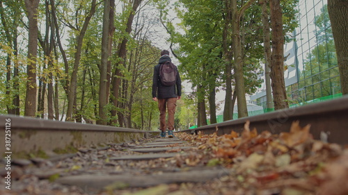 A handsome young man of 18 years in modern warm clothes with a backpack on his shoulders walks on the track, the camera is out of focus. The concept of adolescent loneliness, one in the whole world