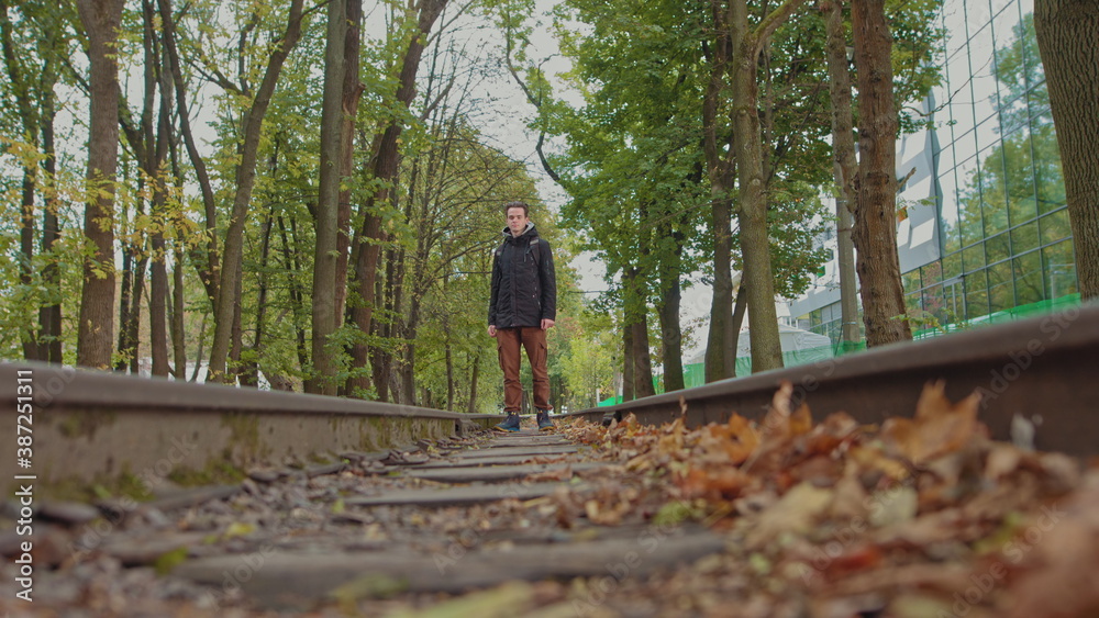 A handsome young man of 18 years in modern warm clothes with a backpack on his shoulders walks on the track, the camera is out of focus. The concept of adolescent loneliness, one in the whole world A handsome young man of 18 years in modern warm clothes with a backpack on his shoulders walks on the track, the camera is out of focus. The concept of adolescent loneliness, one in the whole world