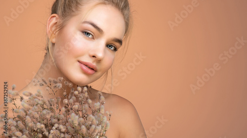 Portrait of young beautiful woman with a healthy  skin of face.  Attractive girl with a bunch spring field flowers