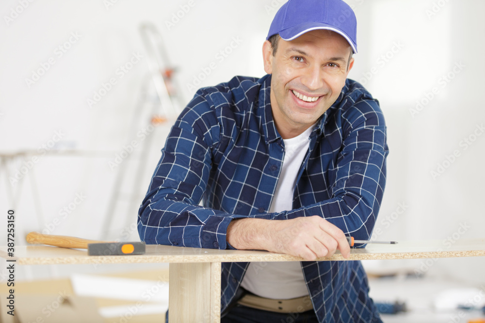 male assembling furniture smilling at camera male assembling furniture smilling at camera