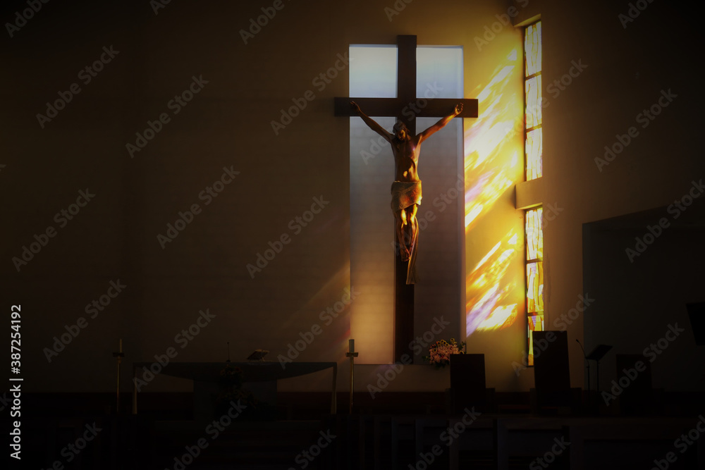 Naklejka premium The crucifixion of Jesus on the cross in the temple, illuminated by the sun through the stained glass windows.
