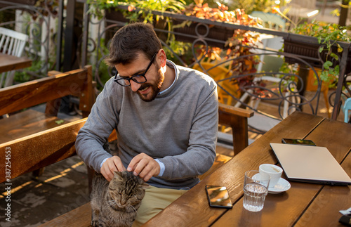 young businessman enjoying with his cat in a cafe 