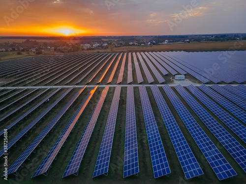 Aerial drone view into large solar panels at a solar farm at bright sunset. Solar cell power plants.