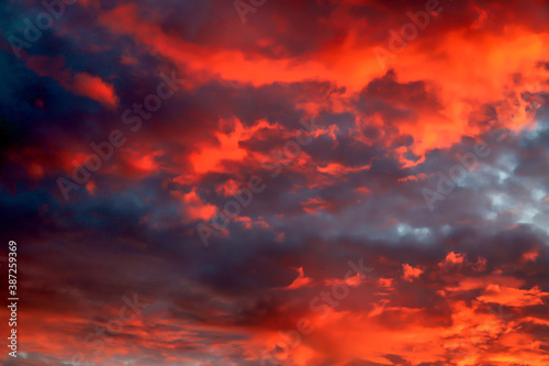 Beautiful red, orange cumulus clouds against a dark sky at sunset in the evening, climate change, global warming. Scenic landscape background, fantasy clouds. © rospoint