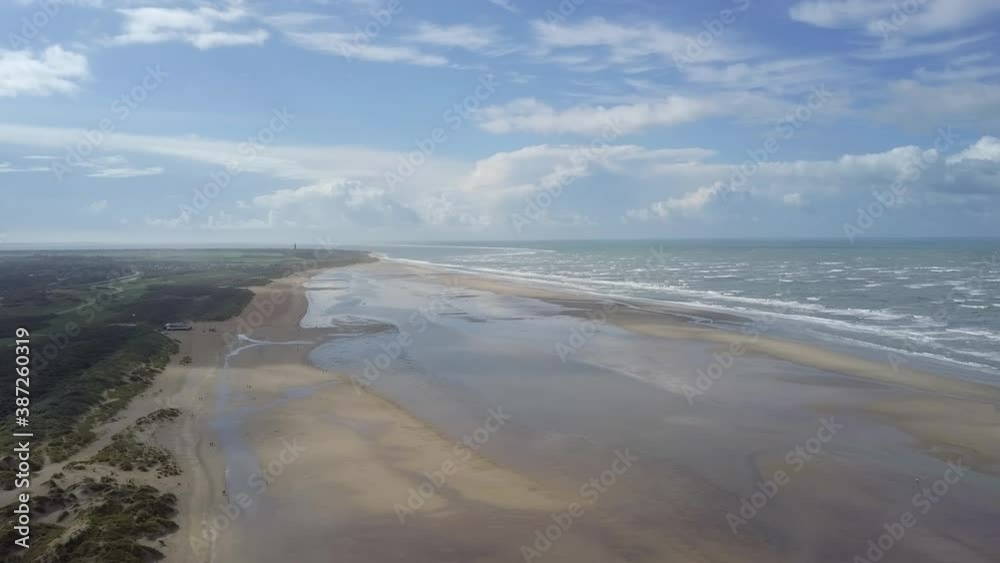 Drone flight high above a wide beach in Ouddorp in the south of the Netherlands. Zeeland. Windy nice weather with waves and interesting clouds in the distance. The camera moves sideways. Drone flight high above a wide beach in Ouddorp in the south of the Netherlands. Zeeland. Windy nice weather with waves and interesting clouds in the distance. The camera moves sideways.