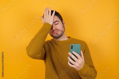 Obraz na plátně Upset depressed Young man wearing casual sweater and over isolated yellow backgr