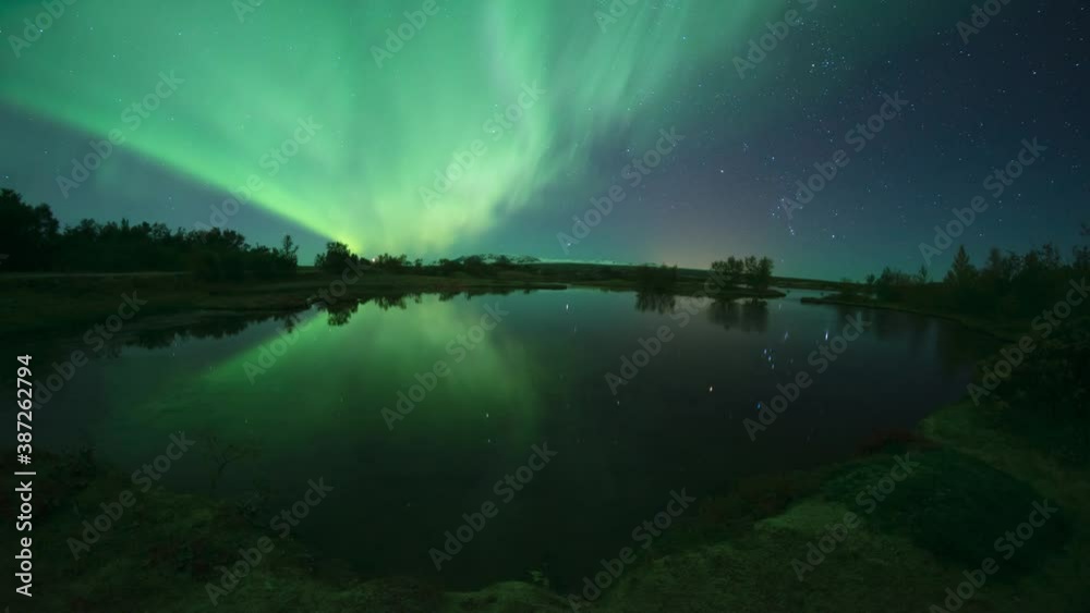 Aurora borealis and stars reflecting in calm water lake Thingvellir Iceland