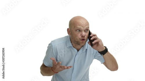 Angry bald guy with beard, wearing casual shirt, yelling at speakerphone, putting mobile phone at ear, trying to prove something, standing mad over white background