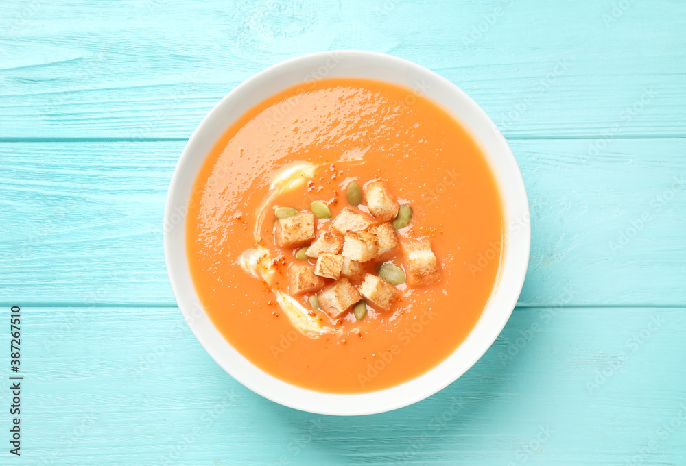 Tasty creamy pumpkin soup with croutons and seeds in bowl on light blue wooden table, top view Tasty creamy pumpkin soup with croutons and seeds in bowl on light blue wooden table, top view