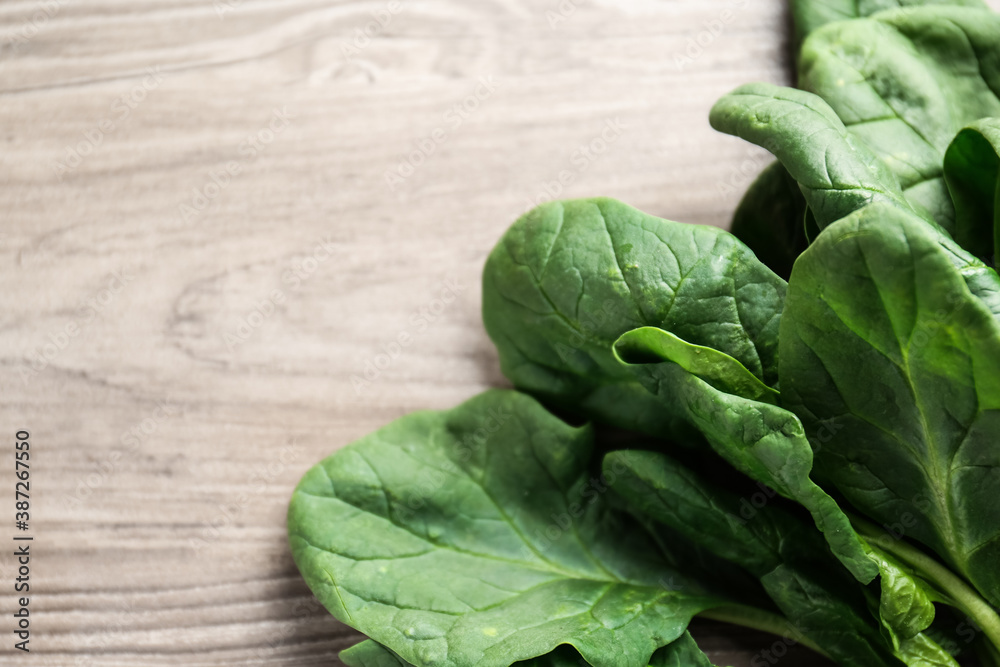 Obraz premium Fresh green healthy spinach leaves on wooden table, closeup