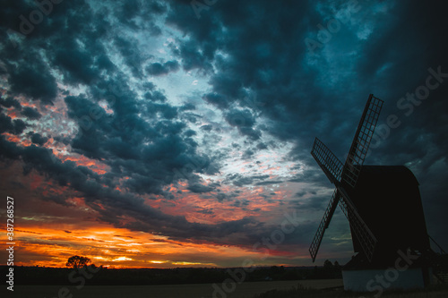Pitstone, United Kingdom - 31 July 2020: Stunning sunset landscape view for Pitstone Windmill with dramatic cloudy sky and beautiful colors of sun setting in red and orange