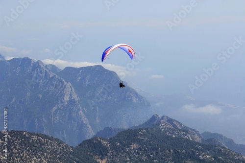 Paraglider flying above Tahtali Mountain in Kemer, Antalya Region, Turkey with Taurus Mountains in background